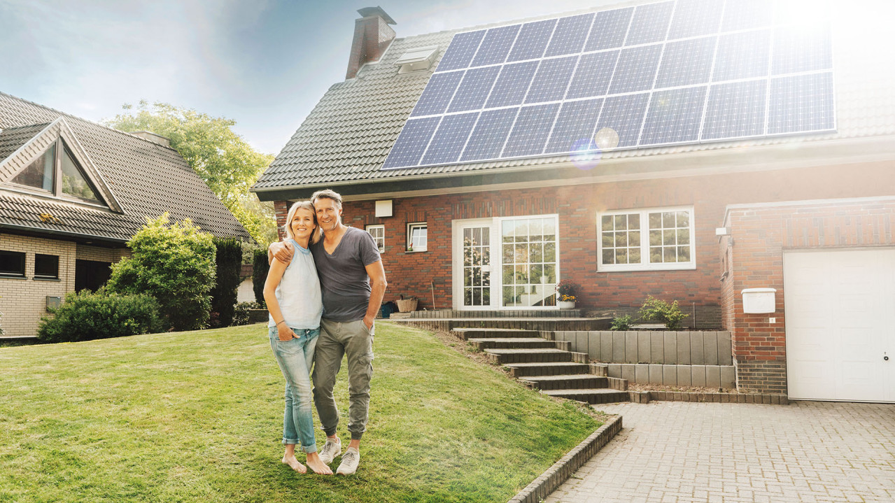 Par framför sitt hus med ett stort solcellssystem.