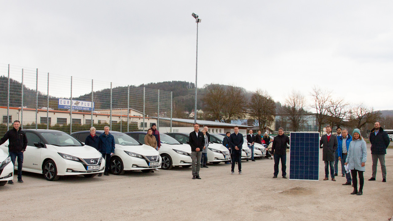 BaseV Projekt mit allen Beteiligten und Elektroautos im Hintergrund.
